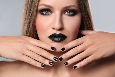 Beautiful woman with stylish nail polish on grey background