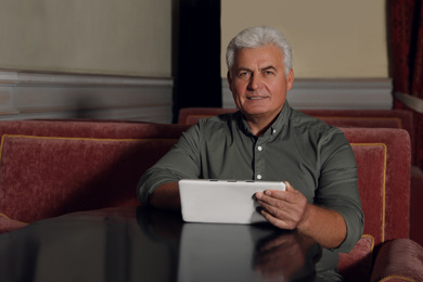 Photo of Senior business owner with tablet in his restaurant