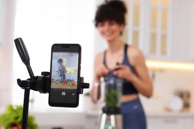 Photo of Food blogger recording video in kitchen, focus on smartphone