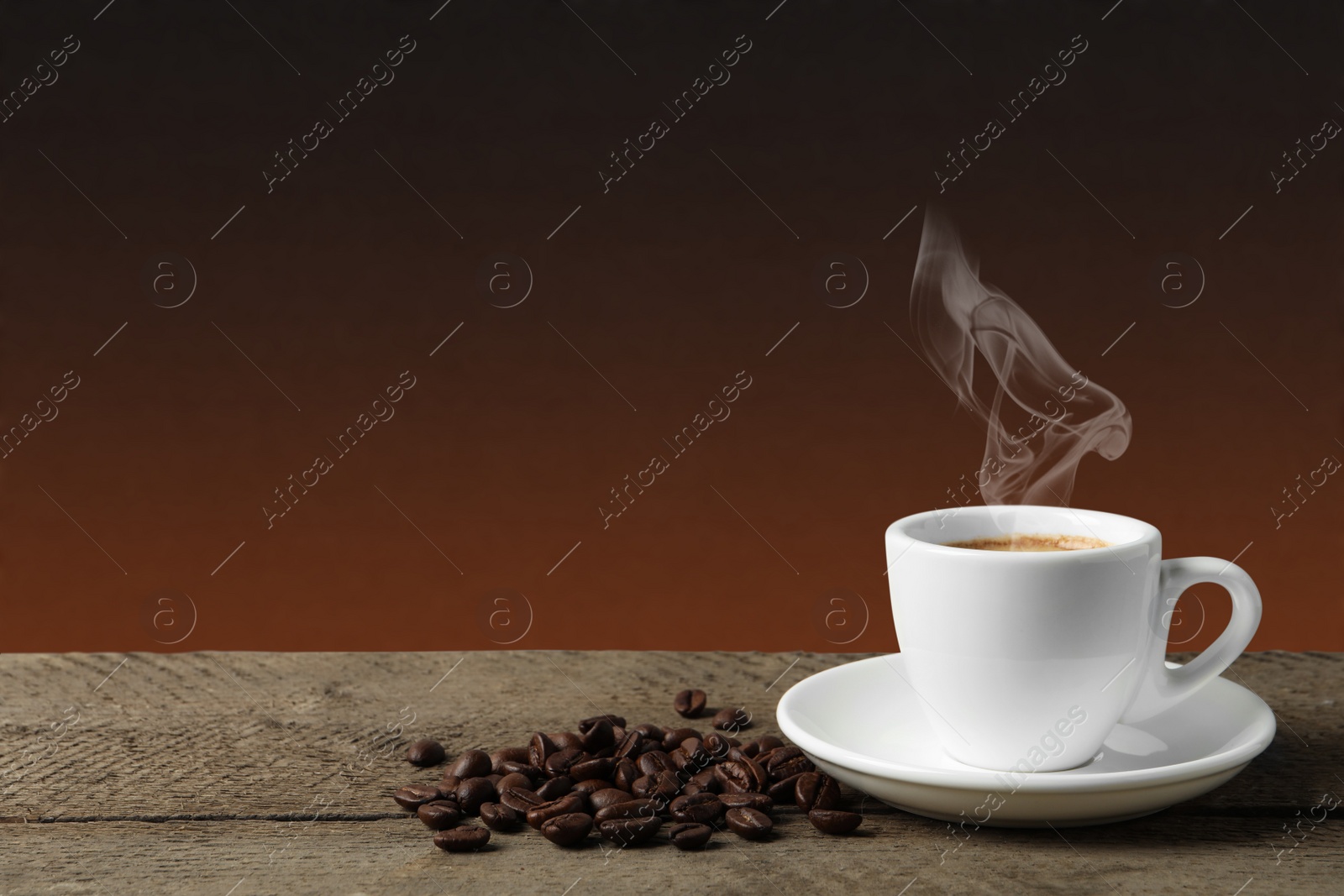 Image of Cup of hot aromatic coffee and roasted beans on wooden table against brown background. Space for text