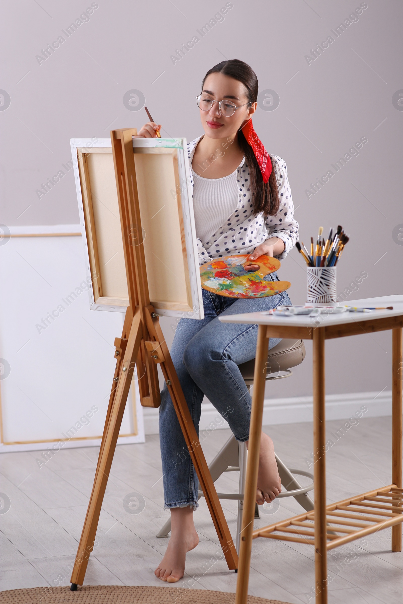 Photo of Happy woman artist drawing picture on canvas indoors