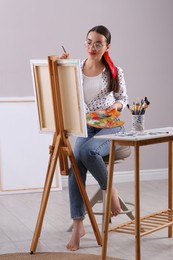 Photo of Happy woman artist drawing picture on canvas indoors