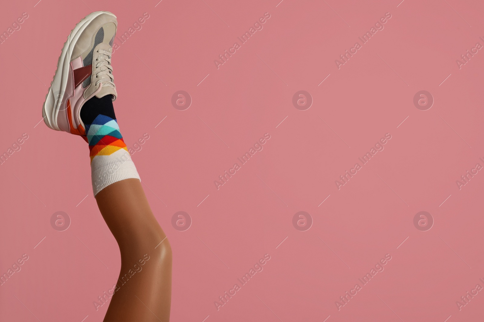 Photo of Woman wearing sneakers on pink background, closeup. Space for text