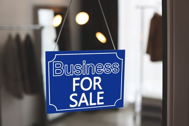 Blue sign with Business For Sale hanging on glass door