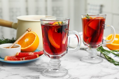 Tasty mulled wine with spices on white marble table