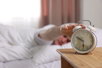 Photo of Man turning off alarm clock in bedroom, focus on hand. Space for text