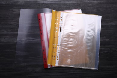 Photo of File folders with punched pockets on black wooden table, flat lay