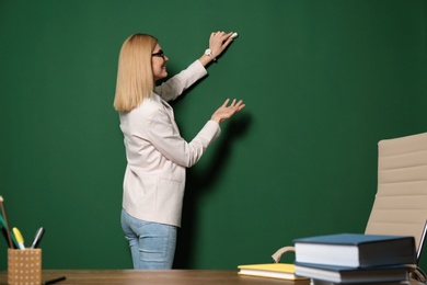 Photo of Beautiful teacher writing on chalkboard, space for text