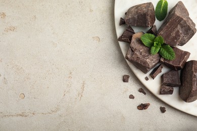 Photo of Tasty dark chocolate pieces with mint on white table, flat lay. Space for text