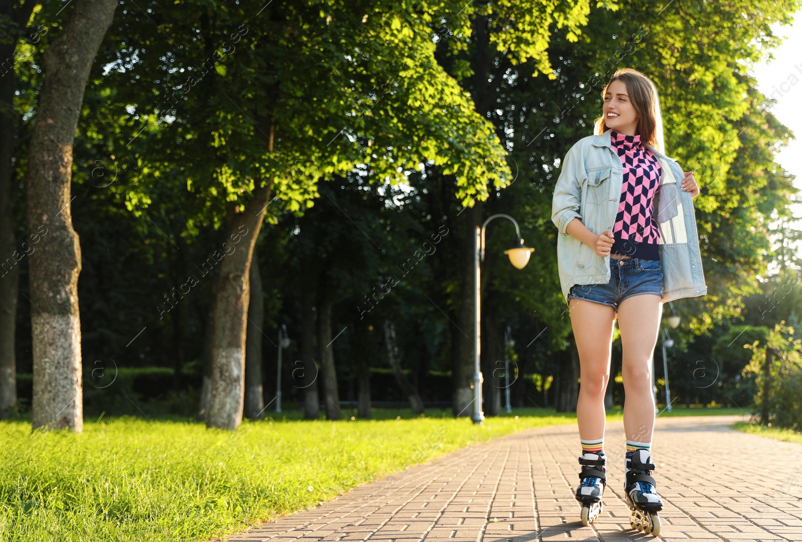 Photo of Beautiful young woman with roller skates having fun outdoors, space for text