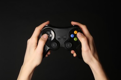 Photo of Woman using game controller on black background, closeup