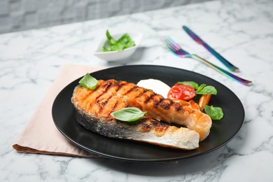 Photo of Plate with tasty salmon steak on table