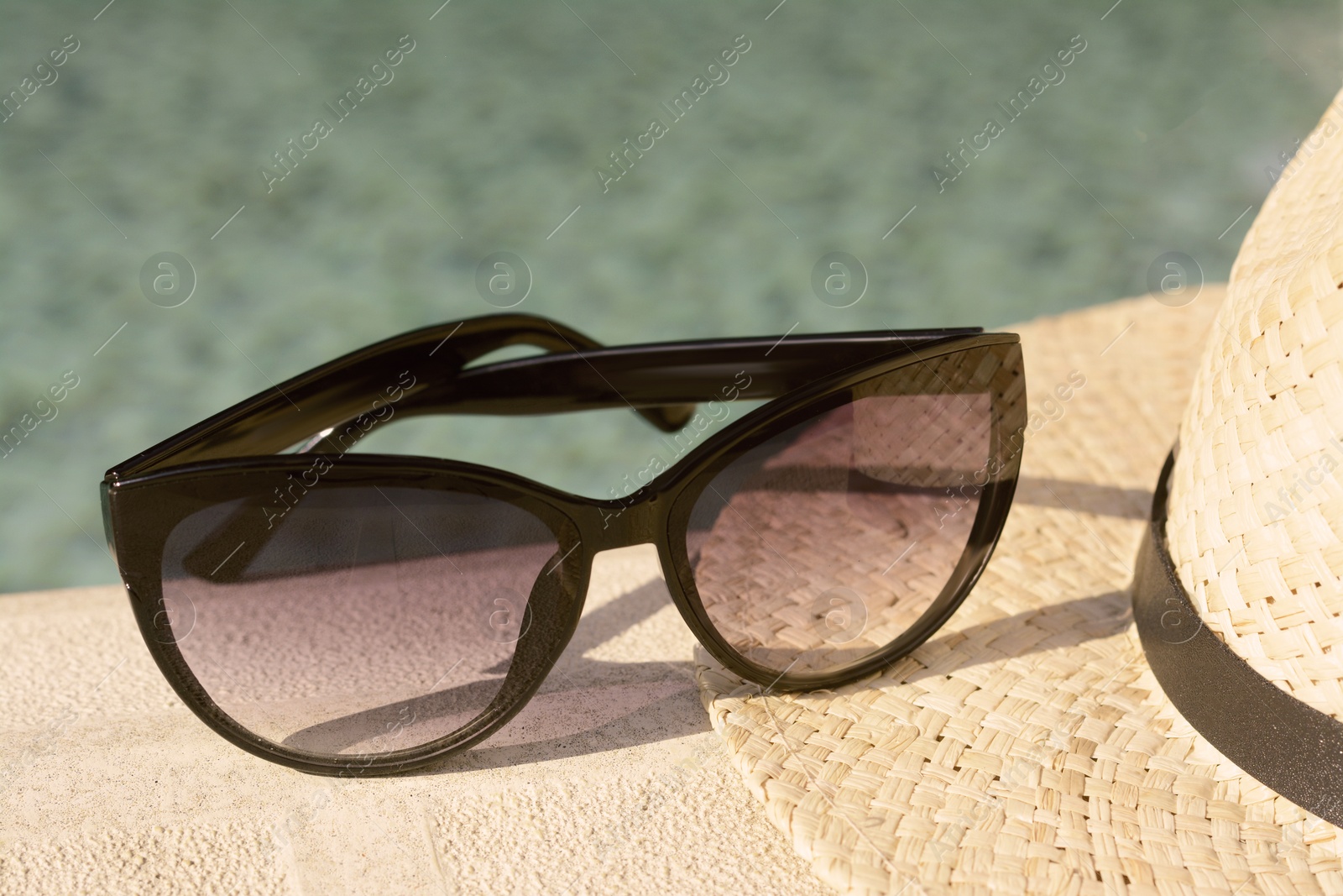 Photo of Stylish hat and sunglasses on blurred background, closeup