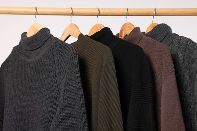 Photo of Rack with different casual sweaters on light background