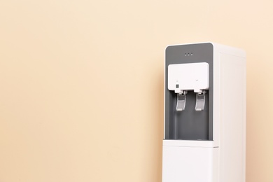 Photo of Modern water cooler against color background with space for text