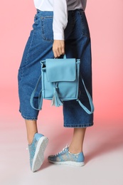 Photo of Woman in stylish shoes with backpack on color background