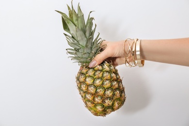 Photo of Woman holding pineapple on light background, closeup