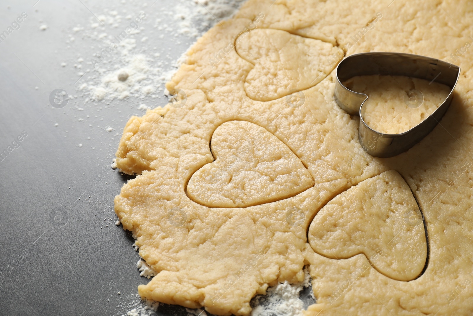 Photo of Making shortcrust pastry. Raw dough and cookie cutter on grey table