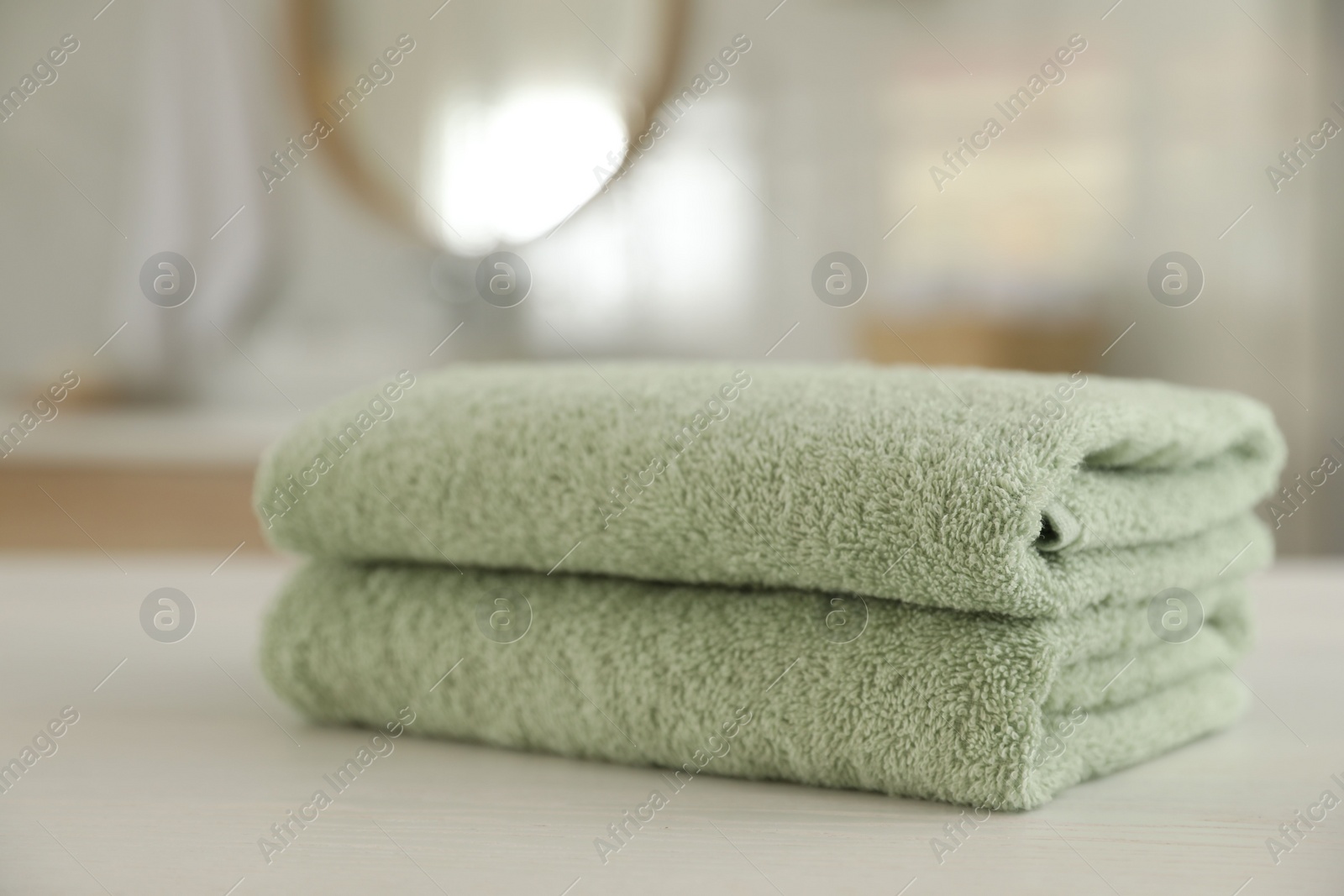 Photo of Stack of clean towels on white wooden table in bathroom