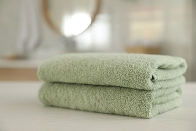 Photo of Stack of clean towels on white wooden table in bathroom