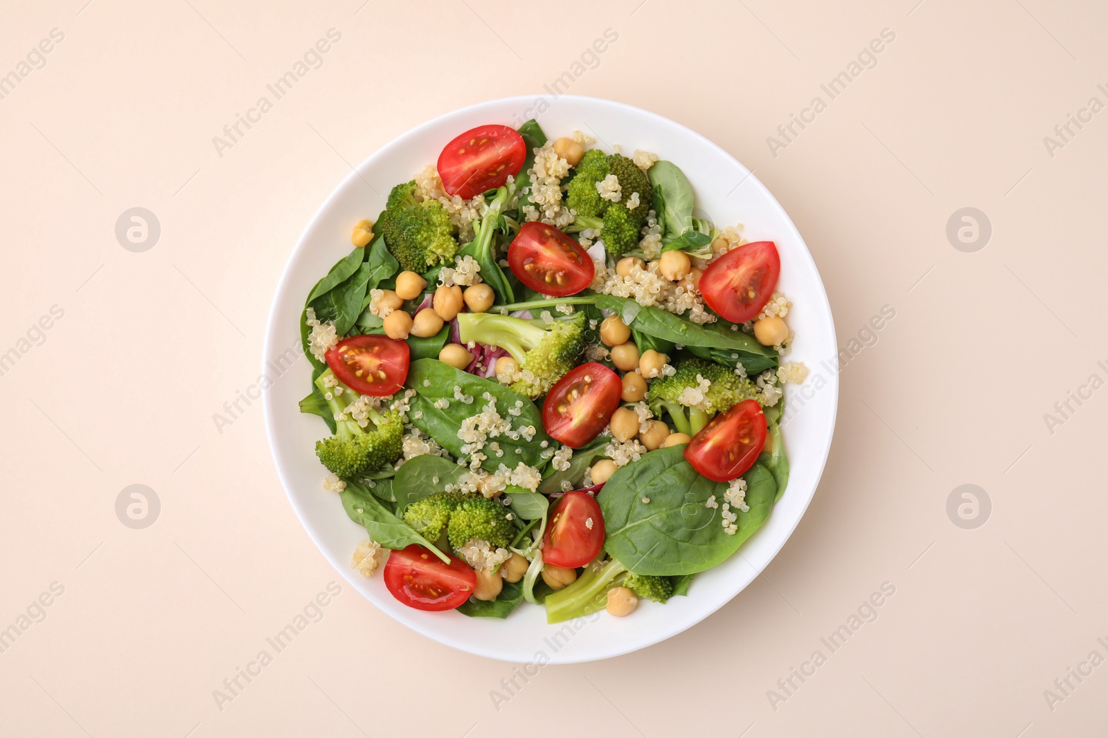 Photo of Healthy meal. Tasty salad with quinoa, chickpeas and vegetables on beige table, top view
