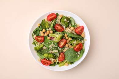 Photo of Healthy meal. Tasty salad with quinoa, chickpeas and vegetables on beige table, top view