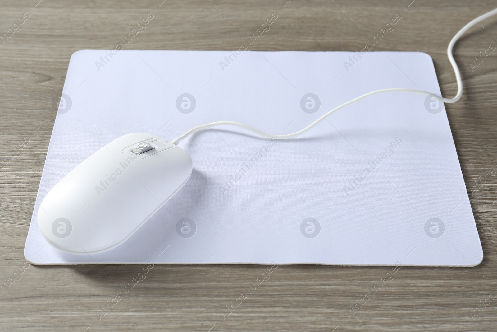 Photo of Wired mouse and mousepad on wooden table