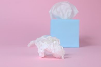 Photo of Used crumpled paper tissue and box on pink background