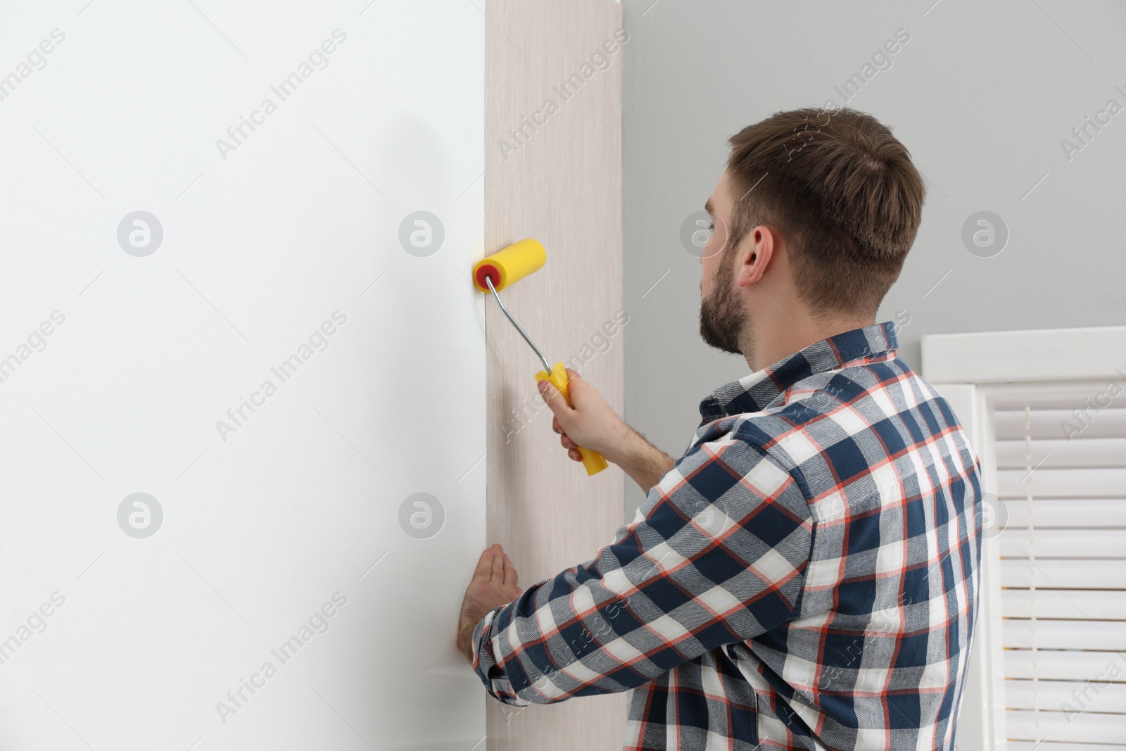 Photo of Man hanging stylish wall paper sheet indoors