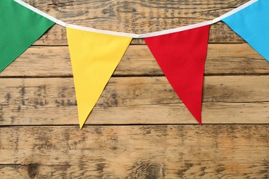 Bunting with colorful triangular flags on wooden background. Festive decor