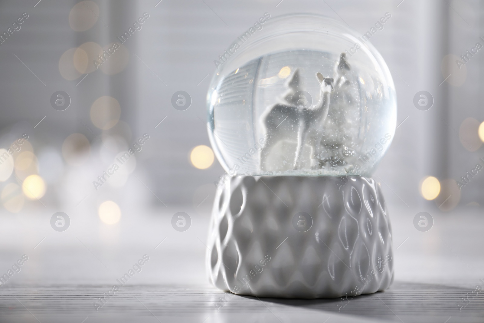 Photo of Christmas snow globe on table. Space for text