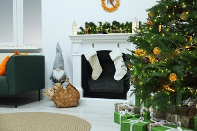 Photo of Cozy living room with fireplace and gifts under Christmas tree. Interior design