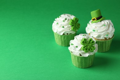 Photo of St. Patrick's day party. Tasty festively decorated cupcakes on green table. Space for text