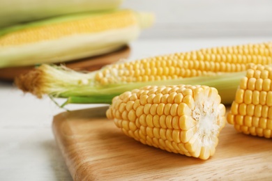 Photo of Tasty sweet corn cobs on wooden board, closeup