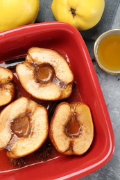 Photo of Tasty baked quinces with honey in dish on grey textured table, flat lay