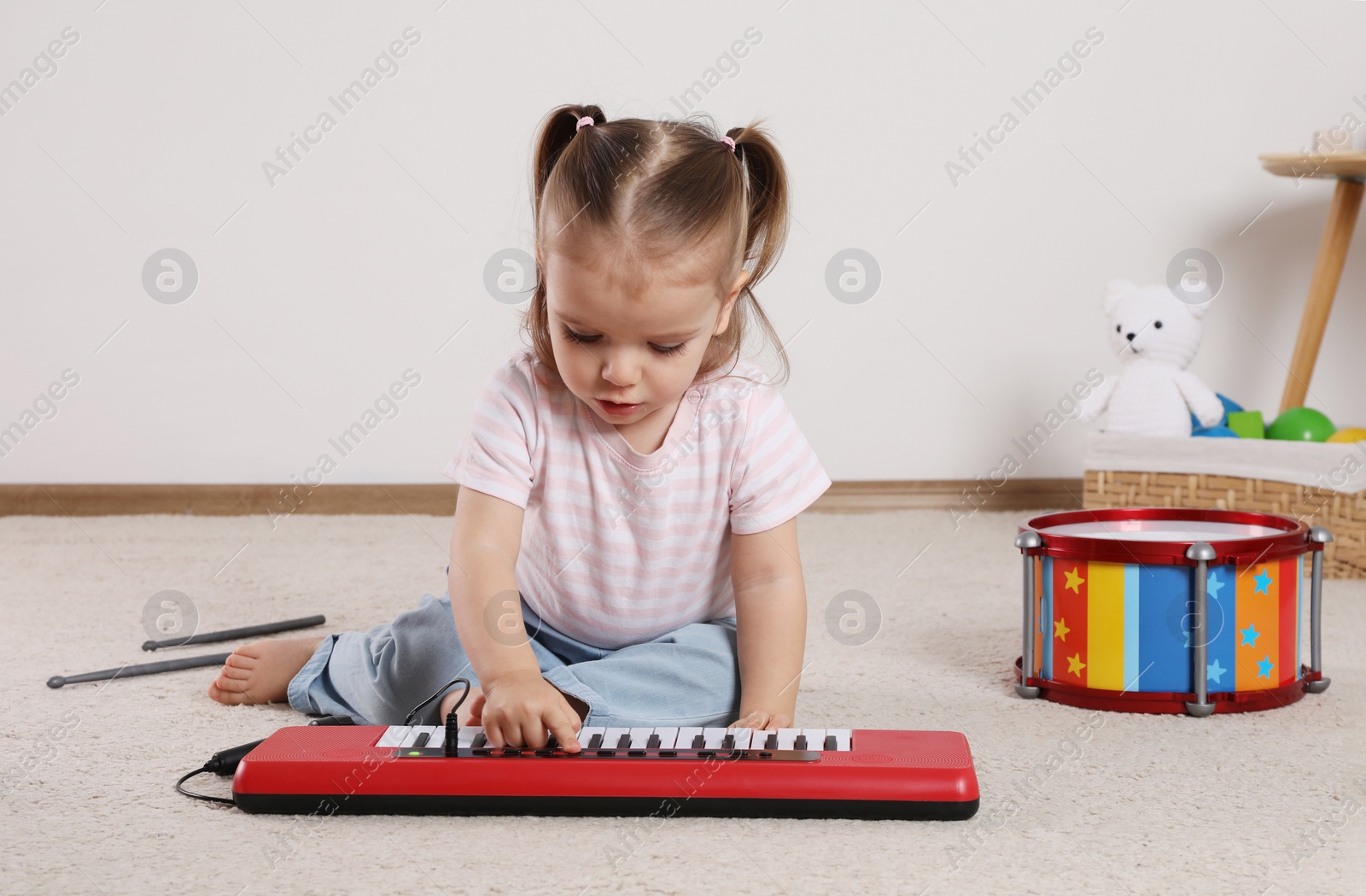 Photo of Cute little girl playing with toy piano at home