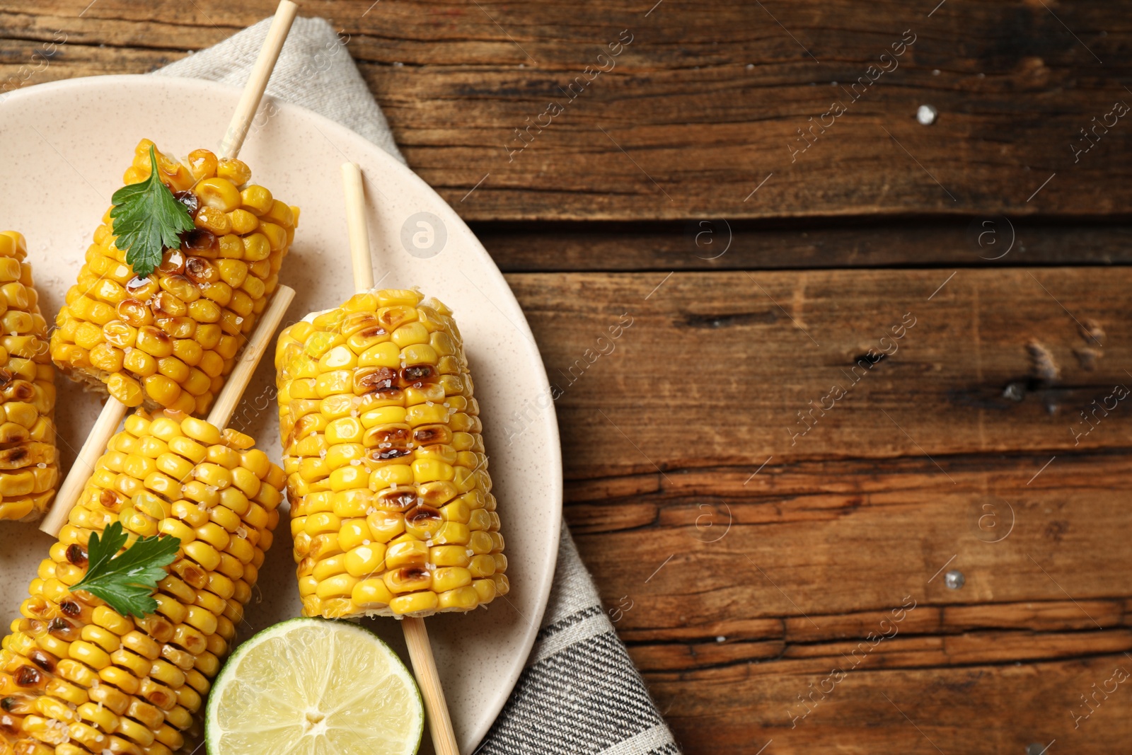Photo of Tasty grilled corn on wooden table, top view. Space for text