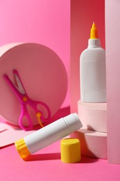 Photo of Composition with glue, paper and scissors on pink background