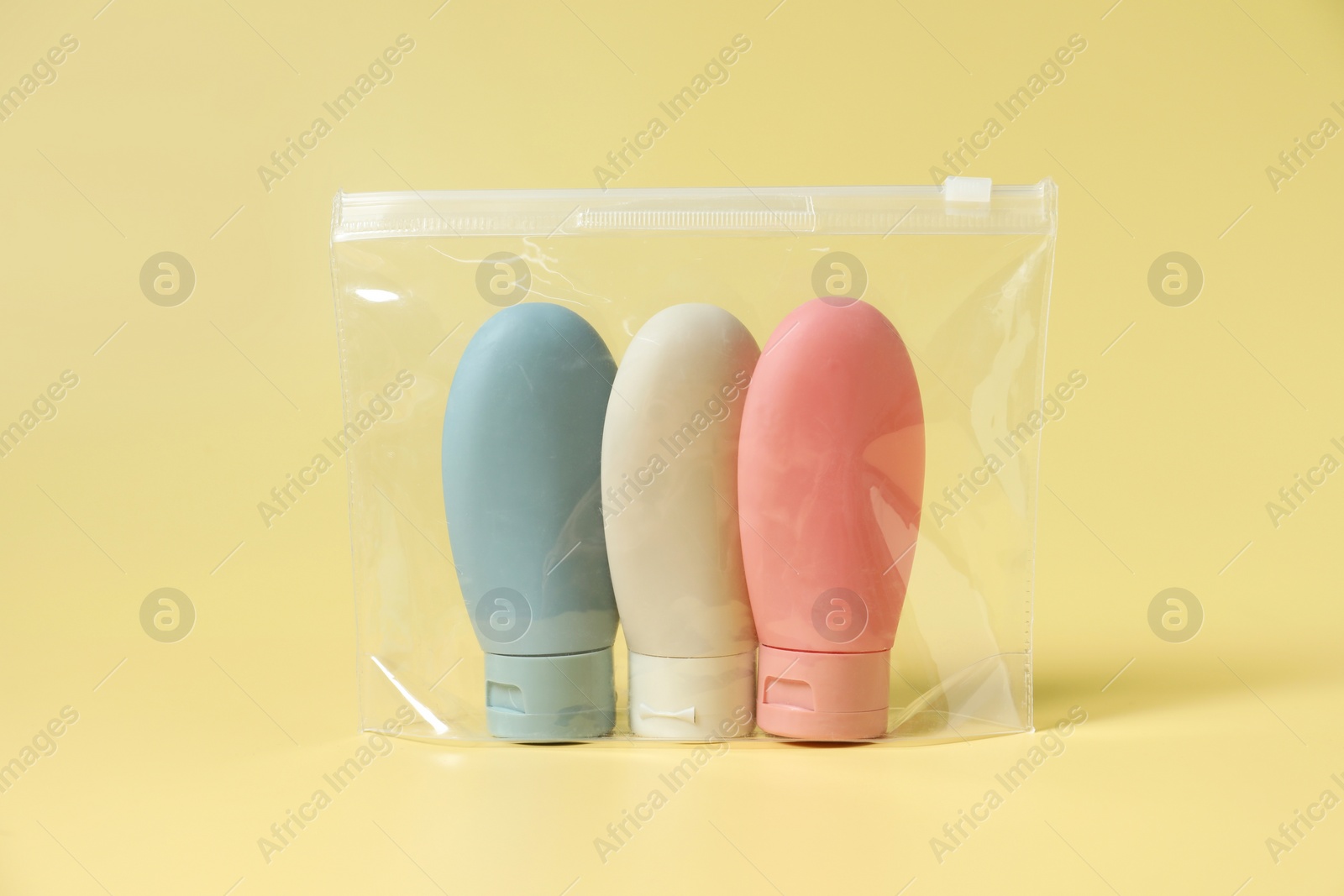 Photo of Cosmetic travel kit in plastic bag on yellow background