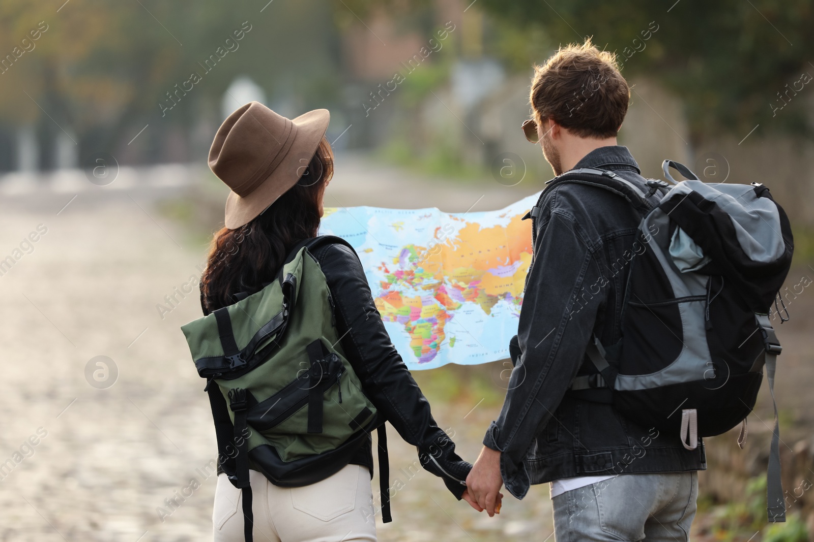 Photo of Couple of travelers with map on city street, back view