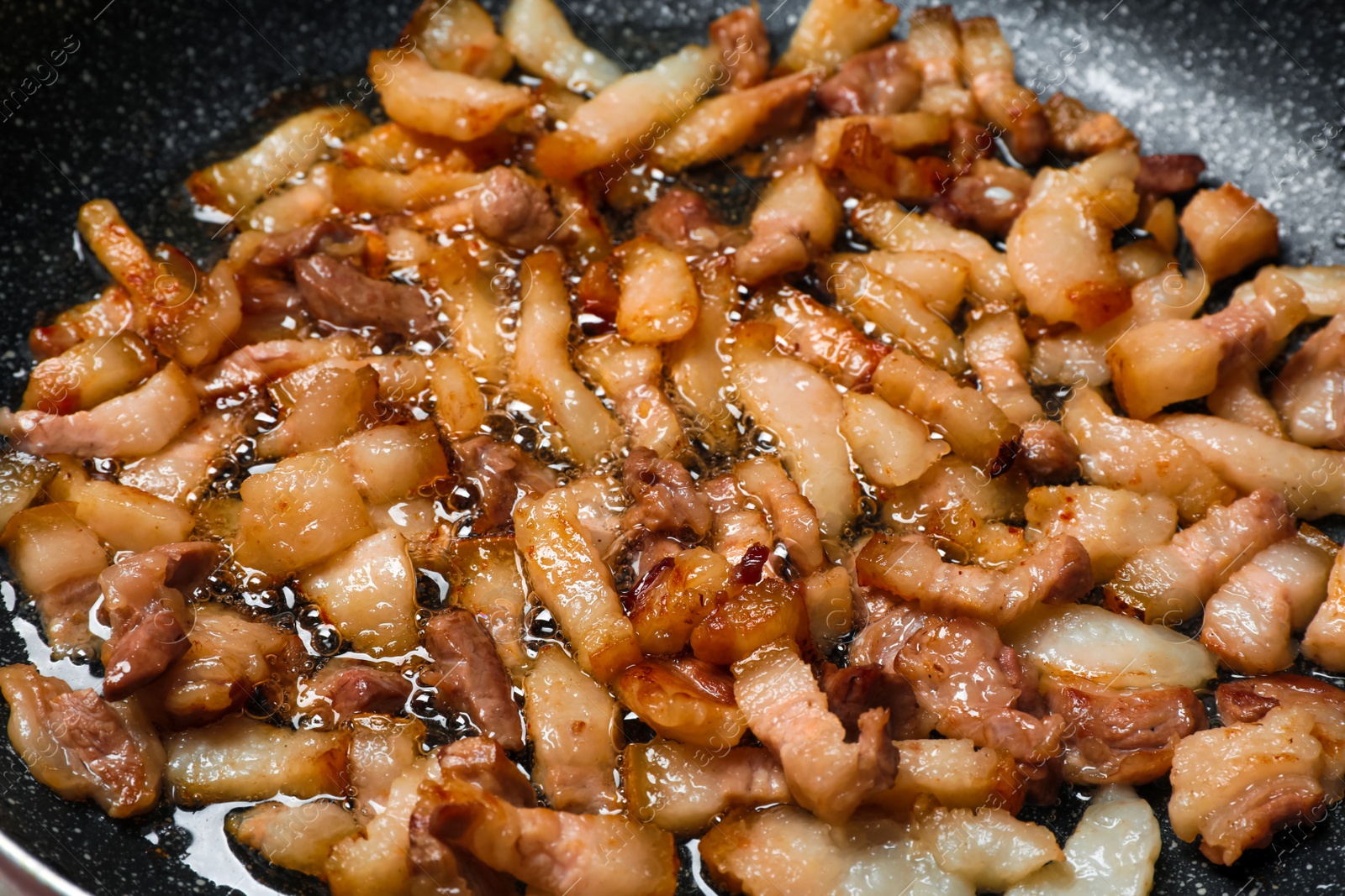 Photo of Frying cracklings in cookware, closeup. Pork lard