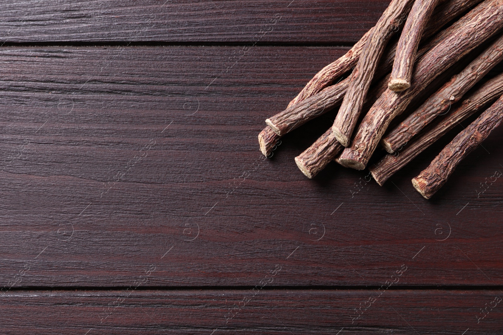 Photo of Dried sticks of liquorice root on wooden table, flat lay. Space for text