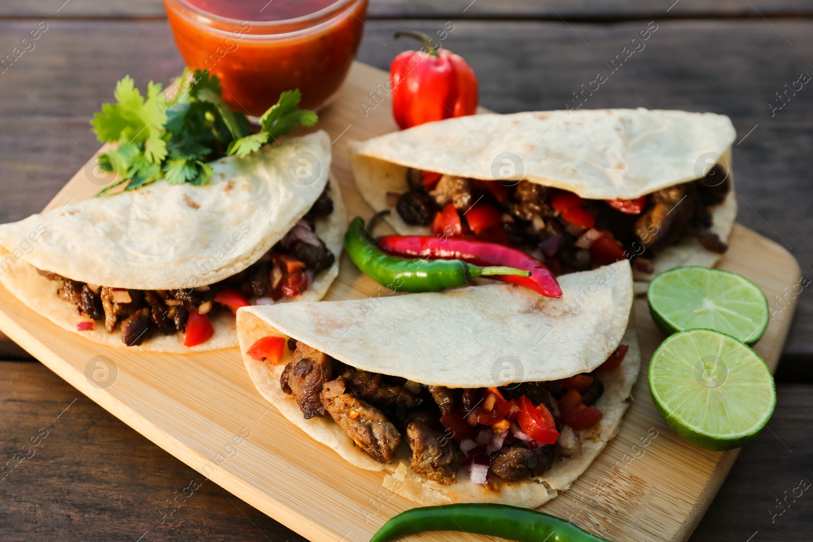 Photo of Delicious tacos with meat, vegetables and sauce on wooden table