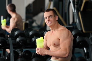 Athletic young man with protein shake in gym