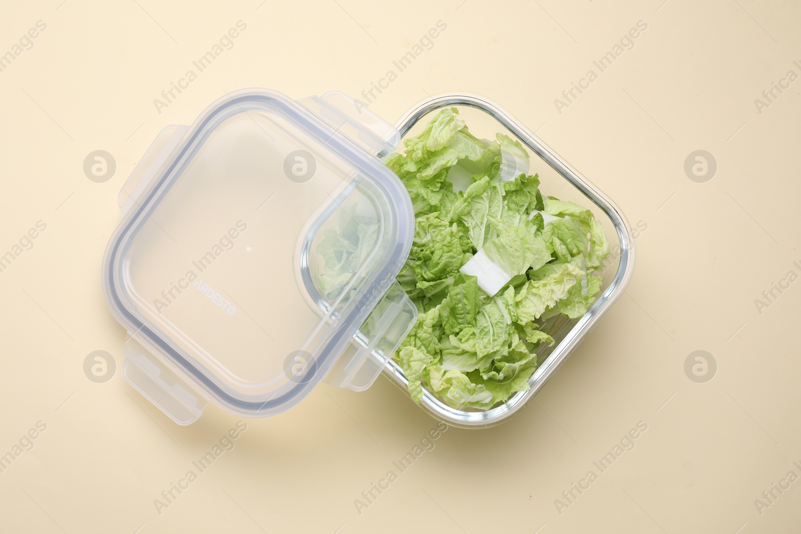 Photo of Glass container with fresh cabbage and lid on beige background, top view
