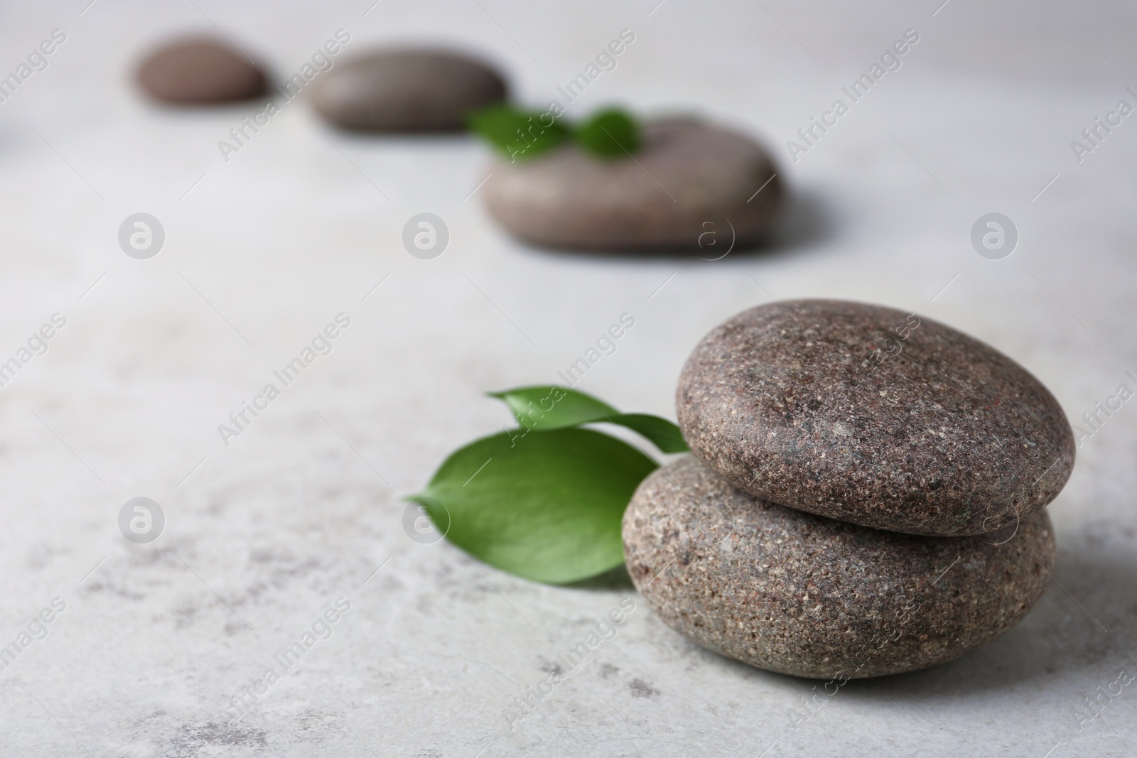 Photo of Spa stones with leaves on grey table. Space for text