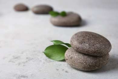 Photo of Spa stones with leaves on grey table. Space for text