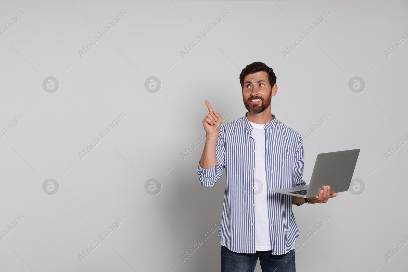 Photo of Handsome man with laptop on light background. Space for text