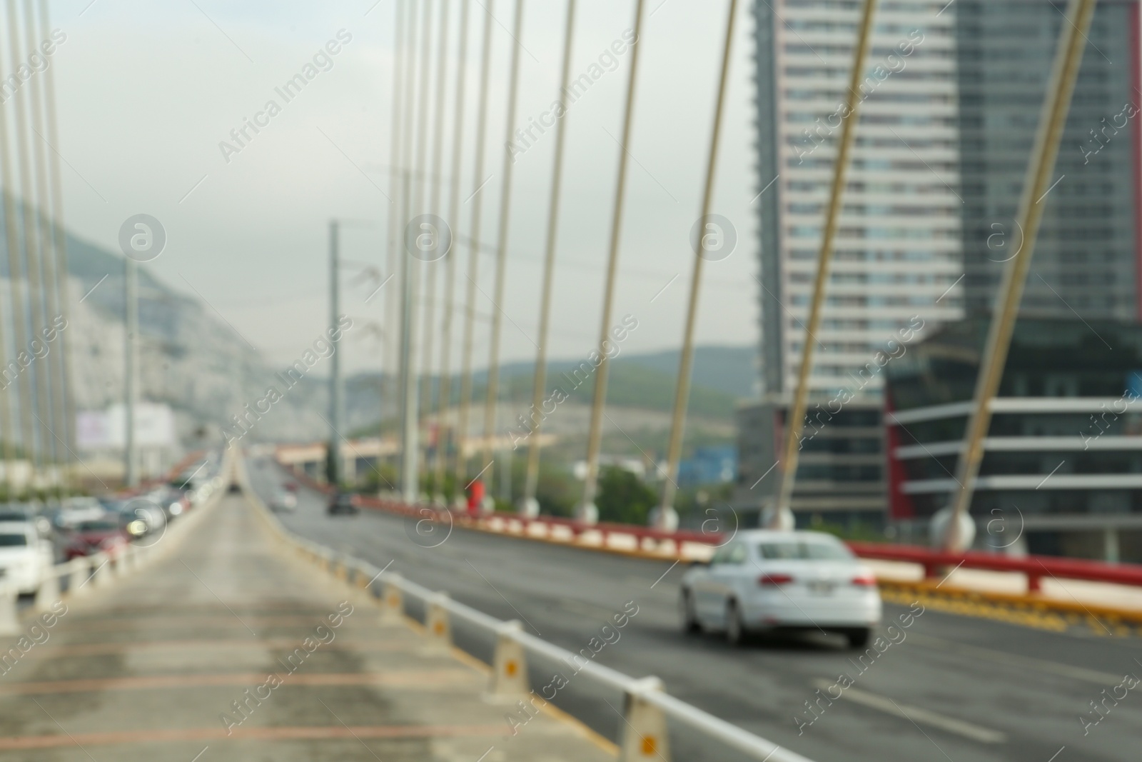 Photo of Blurred view of modern bridge and cars near mountain