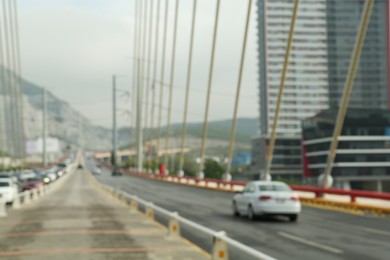 Photo of Blurred view of modern bridge and cars near mountain